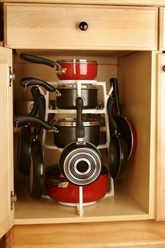 an open cabinet with pots and pans in it