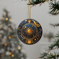 an ornament hanging from a christmas tree decorated with gold stars and moon phases