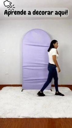 a woman walking across a white rug in front of a purple door with words above it