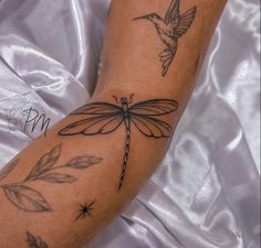 a tattoo on the arm of a woman with a hummingbird and dragonfly attached to it