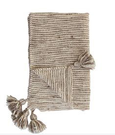 a beige and white blanket with tassels on the ends, folded in two rows