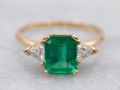 Pretty and luxurious, this emerald and diamond ring has a timeless design. The emerald is a vibrant Kelly green with excellent clarity. The trillion-cut diamonds don't overwhelm the center stone and instead enhance it with just the right amount of sparkle. Highly versatile, this ring is a true classic!Metal: 14K Yellow GoldGem: Emerald 1.41 CaratsGem Measurements: 7.3 x 6.2 mm, Emerald CutAccents: 2 Diamonds totaling .33 Carats, SI in Clarity, H in ColorRing Size: 6.75Marks: “14K*” Stamped on th Emerald Anniversary, Engagement Ring Three Stone, Colombian Emerald Ring, Emerald Ring Vintage, Sapphire Solitaire Ring, Ring Three Stone, Emerald And Diamond Ring, Pink Tourmaline Ring, Sapphire Solitaire