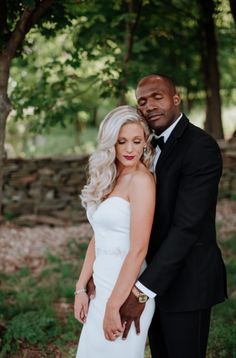 a bride and groom pose for a photo in front of some trees at their wedding