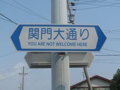 a blue and white sign that says you are not welcome here on a pole with power lines in the background