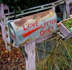 an old mailbox with some plants growing out of it's sides and the words love letters only written on it