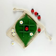 a green object with red and black beads on it sitting in a bag next to other items