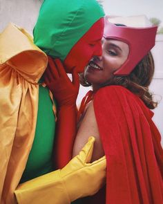 two women dressed in costumes hugging each other with their heads covered by red and green cloths