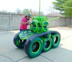 a person standing next to a green toy tank