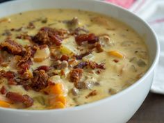 a white bowl filled with soup on top of a wooden table next to a napkin