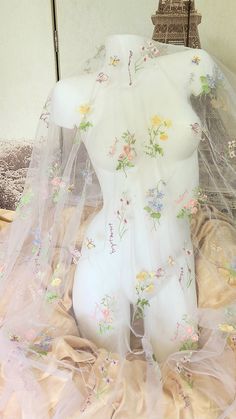 a white mannequin with flowers on it's body covered by a veil