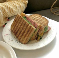 a sandwich is on a plate next to a cup