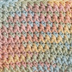 a crocheted blanket is shown in pastel colors