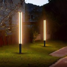 three tall lights are lit up in the grass