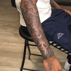 a man with a tattoo on his arm sitting in a chair