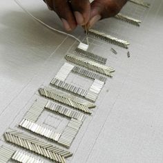 a person working with metal strips on a piece of fabric that is being sewn together