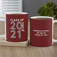 two red coffee mugs sitting on top of a wooden table next to each other