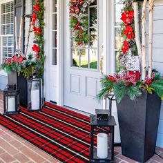 two large planters filled with christmas wreaths sit on the front steps of a house