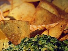 spinach and potato chips are sitting on a plate with dipping sauce in the middle