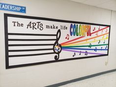 the arts make life community sign is painted on a wall in a school hallway with music notes and rainbow colors