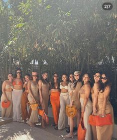 a group of women standing next to each other in bathing suits and holding orange bags