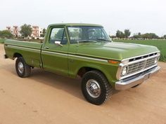 a green pick up truck is parked in the dirt