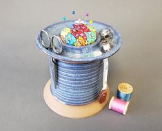 a spool of thread and scissors are sitting on top of a blue bowl with buttons