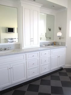 a bathroom with two sinks, mirrors and black and white checkered tile flooring