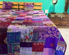 the bed is made up with colorful quilts