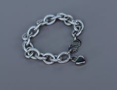 Made from high-quality steel fittings, this chain is very durable and heavy. Each link of the chain has a texture that adds to the longevity of the jewelry. The bracelet features a two-sided, easy-to-use S-shaped clasp and includes a heart-shaped lock charm. The total length of the bracelet is 8 1/4 inches. I can shorten it by removing links; please contact me in advance for adjustments Modern Rolo Chain Link Bracelet, Modern Rolo Chain Bracelet, Modern Silver Rolo Chain Bracelet, Metal Link Bracelets With Rolo Chain, Metal Charm Bracelet With Cable Chain Links, Silver Cable Chain Metal Bracelets, Silver Chain Bracelet With Oval Links, Minimalist Stainless Steel Bracelet With Chunky Chain, Silver Cable Chain Bracelet