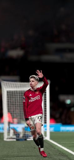 a soccer player is running on the field with his arms in the air as he prepares to kick the ball