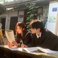 two people sitting at a table with papers in front of them and one person holding a pen