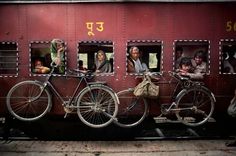 several people are looking out the window of a train car with bicycles parked on it