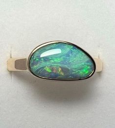 Blue and Green Boulder Opal Ring in 14K Yellow Gold. Australian opal ring in solid 14K yellow gold. Currently Size US 9 1/4 (sizable at check out) 3mm X 1.4mm Solid 14k yellow gold band. Australian Boulder Opal: 2.82 Carats 12.55mm X 7.45mm All of our creations are made out of 14K Gold (Yellow, White, Rose) or 925 Sterling Silver, None are filled or electroplated.  All of our stones are Nature-made, therefore some natural flaws may be present. Hand crafted in the We Work Gems Shop in Washington Boulder Opal Jewelry, Cable Reel, Boulder Opal Ring, Australian Opal Ring, Gem Shop, Australian Boulder Opal, Blue Band, Opal Earrings, Opal Ring