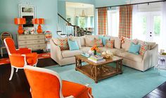 a living room filled with furniture next to a window covered in orange and blue curtains