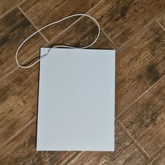 a white piece of paper sitting on top of a wooden floor next to a string