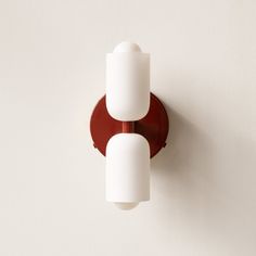 two white lights mounted on the side of a wall next to a brown light fixture