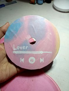 a hand holding a pink and blue disc with the words lover koon on it