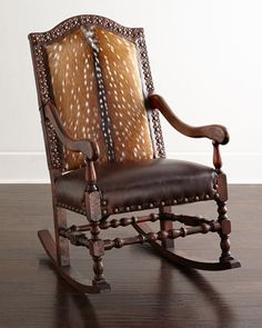 an old rocking chair with deer hides on the back and arm rests on a wooden floor