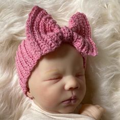 a newborn baby wearing a pink knitted bow hat