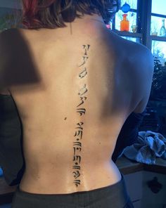 the back of a woman's body with writing on her upper and lower back