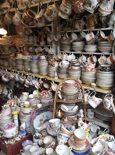 there are many plates and bowls on the shelves in this room, all stacked together