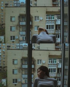 a woman is sitting in a chair looking out the window at some buildings and windows