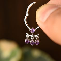 Amethyst has been a symbol of royalty for centuries. Its deep purple color is associated with luxury, wealth, and power and is believed to have healing and protective powers. This unique septum clicker is crafted in solid 14k or 18k gold, with dangling Amethysts, for the subtle charm. It is a stunning addition to our collection and will be for your setup too. The hinged click mechanism makes it secure.  VERTICAL INNER LENGTH OF HOOP: 8mm (ALL IMAGES) *  Gold: 14k / 18k Solid Gold  *  Gold Colour Internally Threaded Crescent Jewelry As Gift, Crescent Internally Threaded Jewelry As Gift, Crescent Internally Threaded Jewelry For Gifts, Crescent Hallmarked Sterling Silver Jewelry, Crescent-shaped Hallmarked Sterling Silver Jewelry, Hallmarked Crescent Sterling Silver Jewelry, Elegant Small Hoop Sterling Silver Septum Ring, 14k Gold Septum Ring With Prong Setting As Gift, Dainty Amethyst Jewelry In White Gold