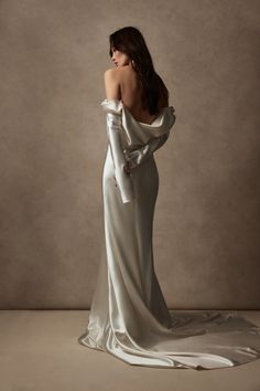 the back of a woman in a white dress with long sleeves and an open shoulder