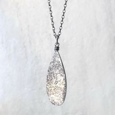 This teardrop pendant necklace is handmade from solid sterling silver. I have cut a teardrop from a sheet of silver using my jeweler's saw. I then used a variety of vintage hammers to create its unique texture. I have attached the bail with a wire-wrapped loop and suspended the pendant along a sterling silver chain. The chain features a 3-inch extender which allows it to be slightly adjustable. The silver has been oxidized and polished to create an antique patina finish.Be sure to see all photos and video for size and color reference.Teardrop Size: About 15x40mmSelect your necklace length when ordering. Total necklace length is measured from end to end and includes all parts of chain and clasp.The necklace photographed is shown at an 18-inch length modeled on a women's size S/M mannequin w Silver Sterling Drop For Gifting, Handmade Sterling Silver Pendant Drop Necklace, Nickel Free Sterling Silver Drop Necklace, Sterling Silver Drop Necklace With Large Pendant, Handmade Silver Teardrop Necklaces, Sterling Silver Teardrop Pendant Jewelry, Sterling Silver Teardrop Necklaces Engraved, Handmade Silver Teardrop Necklace, Silver Teardrop Necklace With Large Pendant