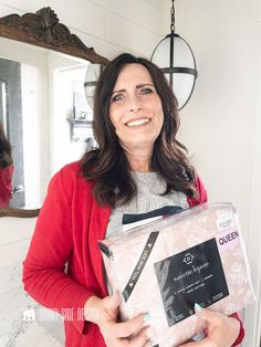 a woman holding a box in front of a mirror