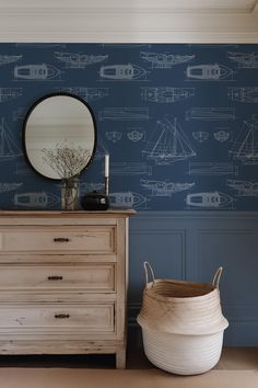 a dresser with a mirror and a basket on it in front of a blue wall