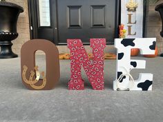 the letters are made out of wood and decorated with cow print fabric, along with a black door