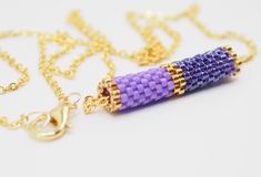 a purple and gold beaded necklace on a white surface with a chain attached to it