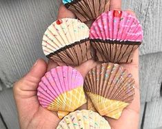 there are five seashells in the palm of someone's hand, with sprinkles on them